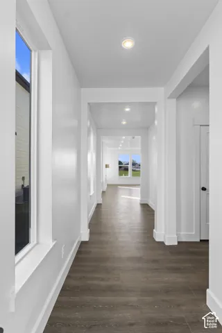 Wood-finish flooring extending through the hallway, recessed ceiling lighting, and white walls