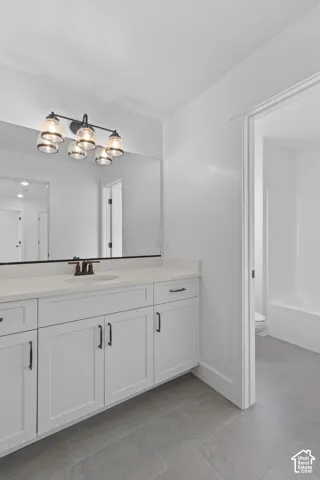 Double vanity with white cabinetry, a light-toned countertop, and a large mirror