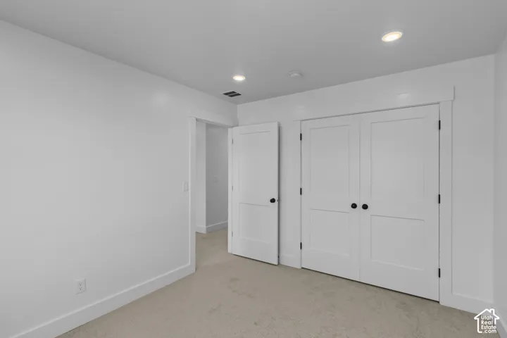 Carpeted flooring with white trim, recessed ceiling lighting, and a white paneled door with black hardware