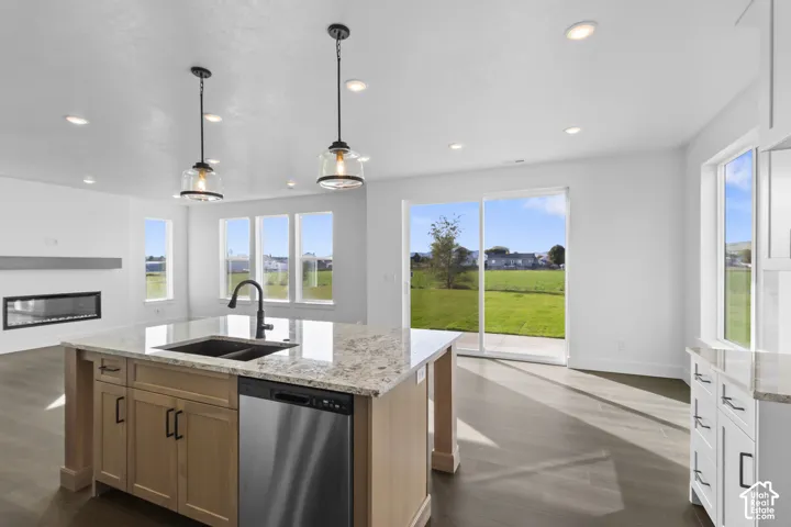 Open-concept interior featuring wood-finish flooring, a kitchen island with granite countertops, a built-in fireplace, and expansive windows