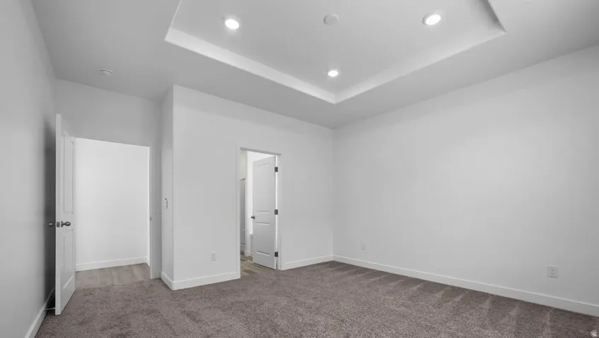 Tray ceiling with recessed lighting and neutral carpeting