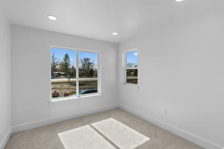 Recessed lighting illuminates the room, featuring two windows and wall-to-wall carpeting