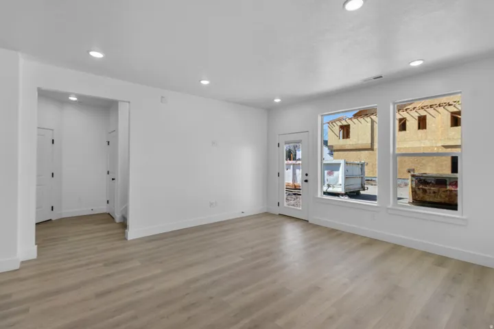 Spacious room featuring wood-finish flooring, recessed lighting, and multiple windows