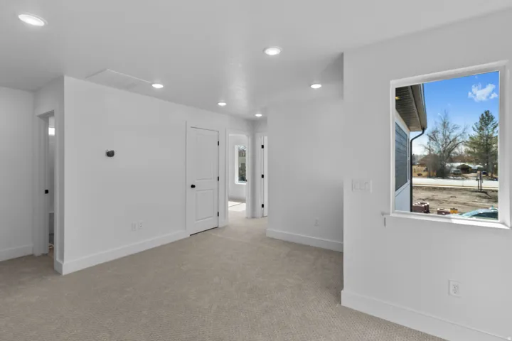 Recessed ceiling lighting, light-toned carpeting, white interior doors, a white window frame, and white walls