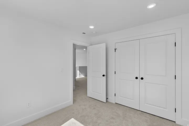Recessed lighting, light gray carpeting, white trim, and white paneled doors with matte black hardware