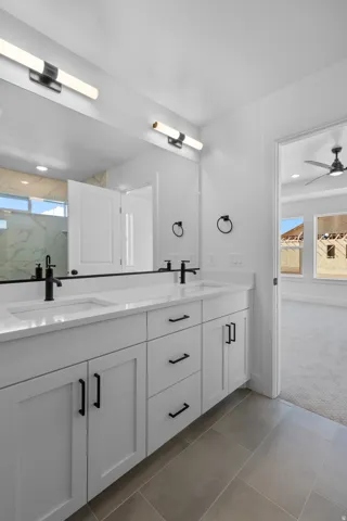 Double vanity with white cabinetry, black hardware, integrated sinks, and contemporary lighting fixtures