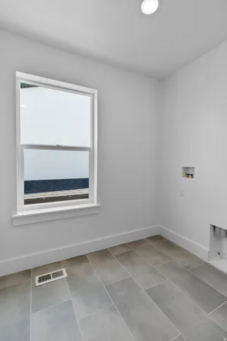 Recessed ceiling lighting, a white framed window, and large format tile flooring