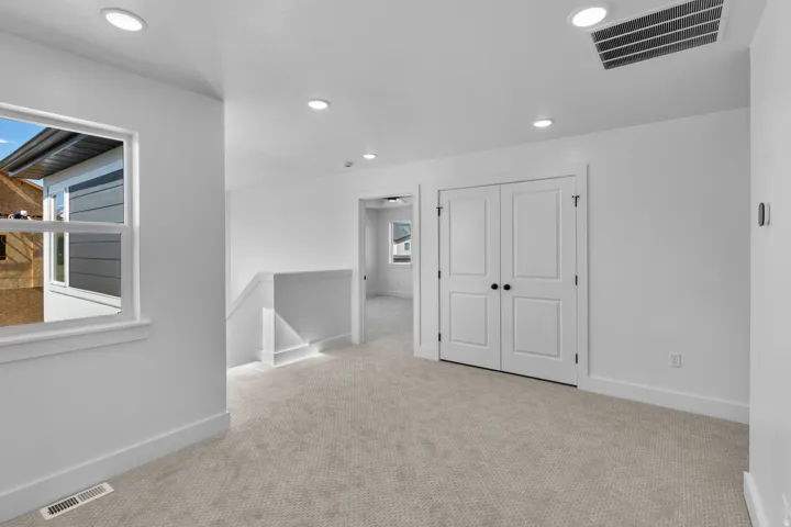 Recessed ceiling lighting, light-toned carpeting, white double doors, white window trim, and white walls