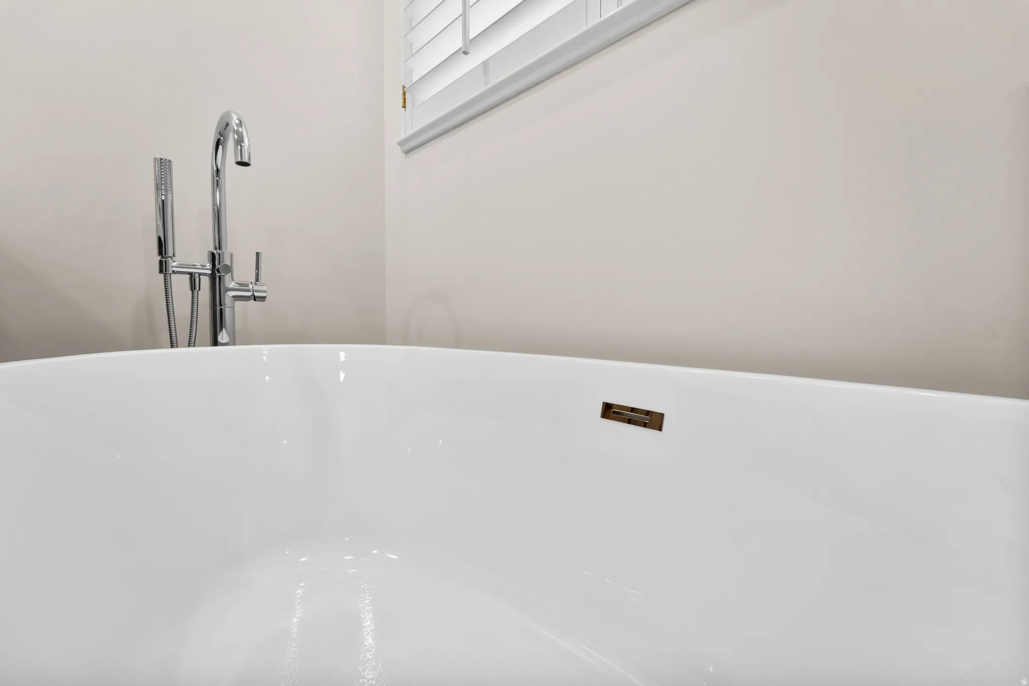 Freestanding soaking tub with a polished chrome floor-mounted tub filler and handheld shower attachment