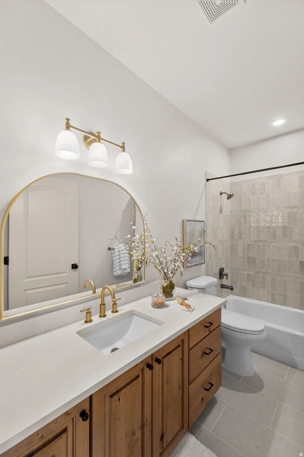Integrated vanity with wood-finish cabinetry, white countertop, and gold-finish fixtures