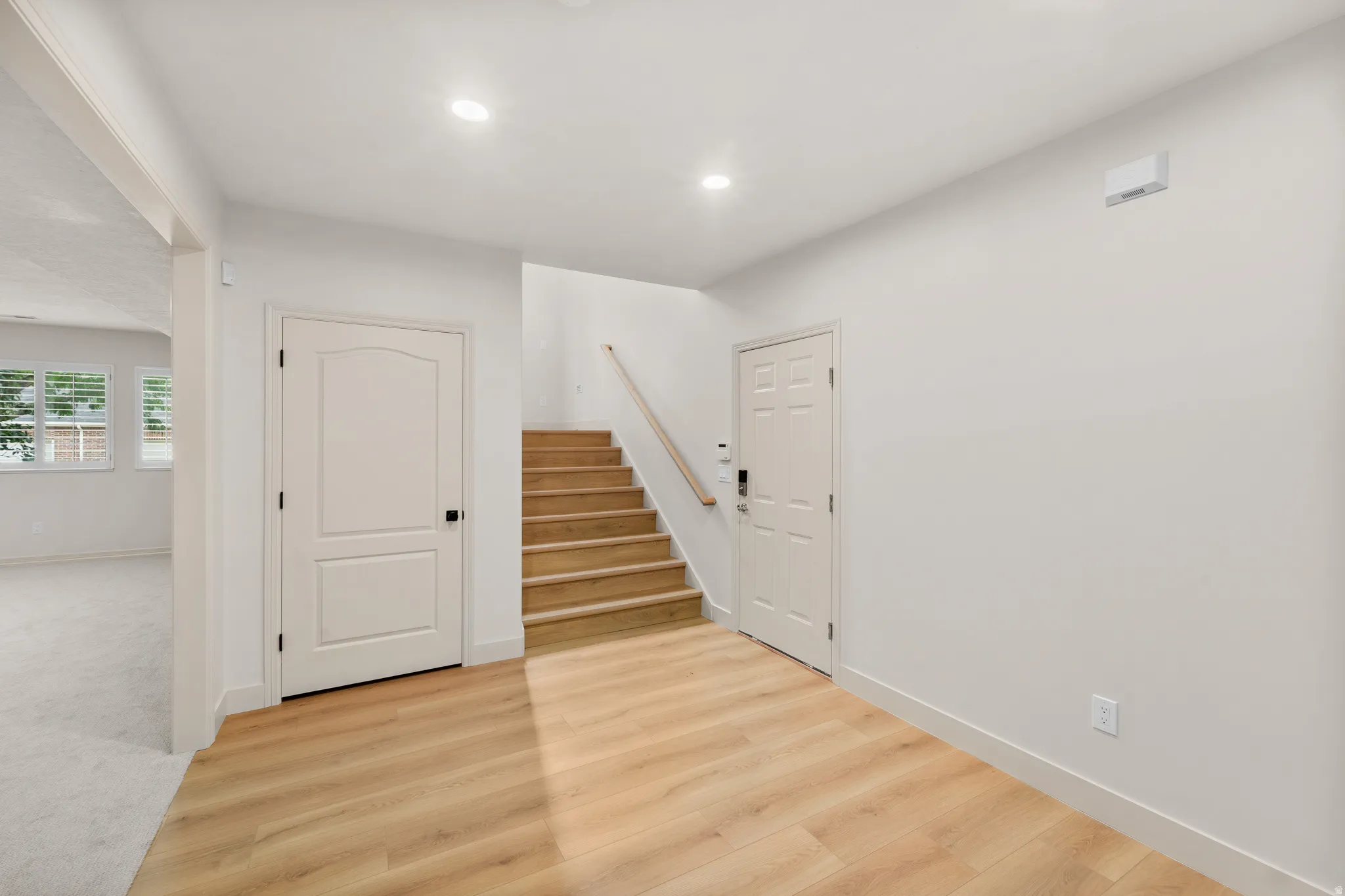 Wood-finish flooring, recessed lighting, light wood staircase, white interior doors, and neutral wall tones