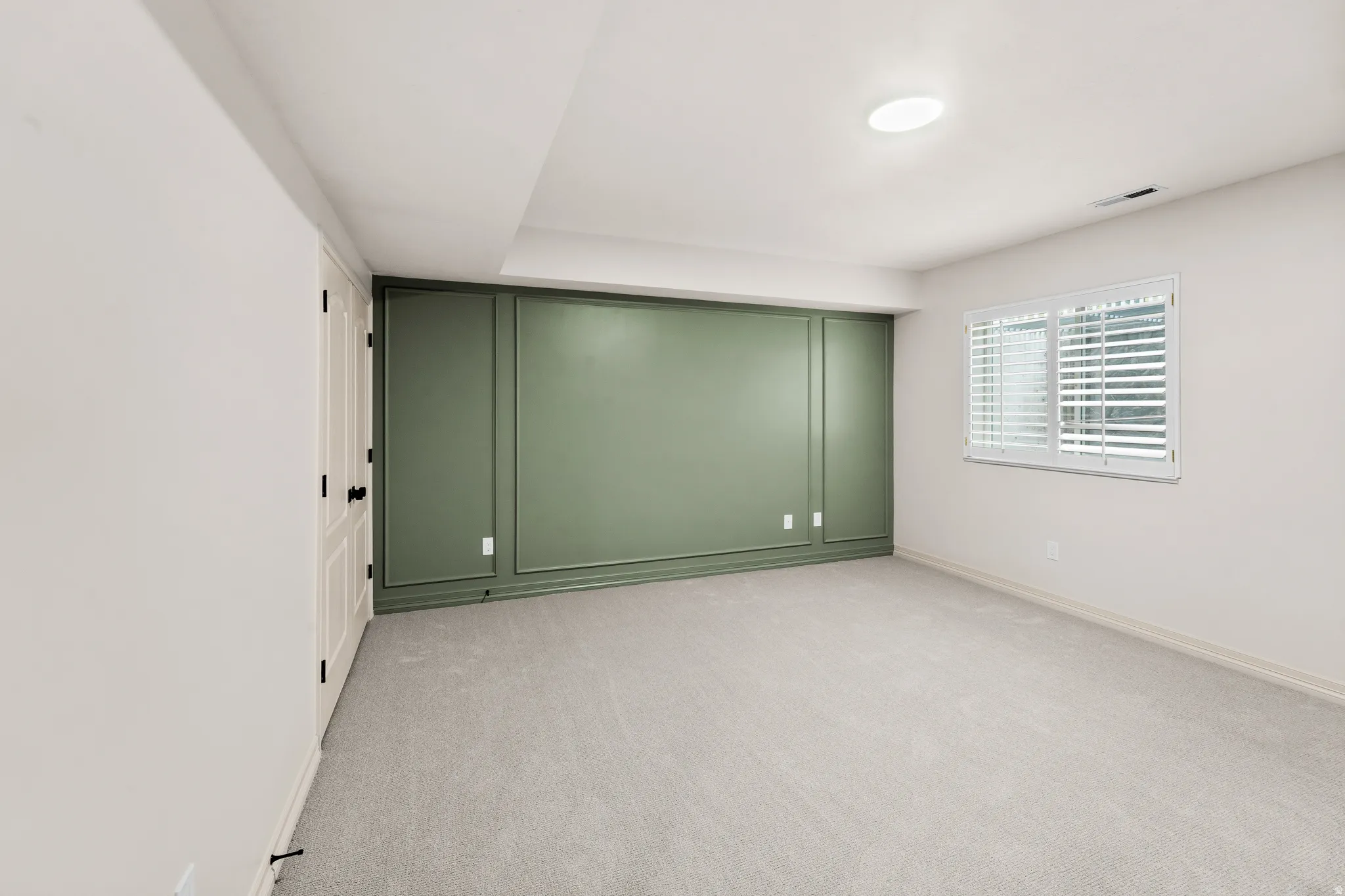 Wall paneling accent, recessed lighting, wall-to-wall carpeting, and a window with plantation shutters