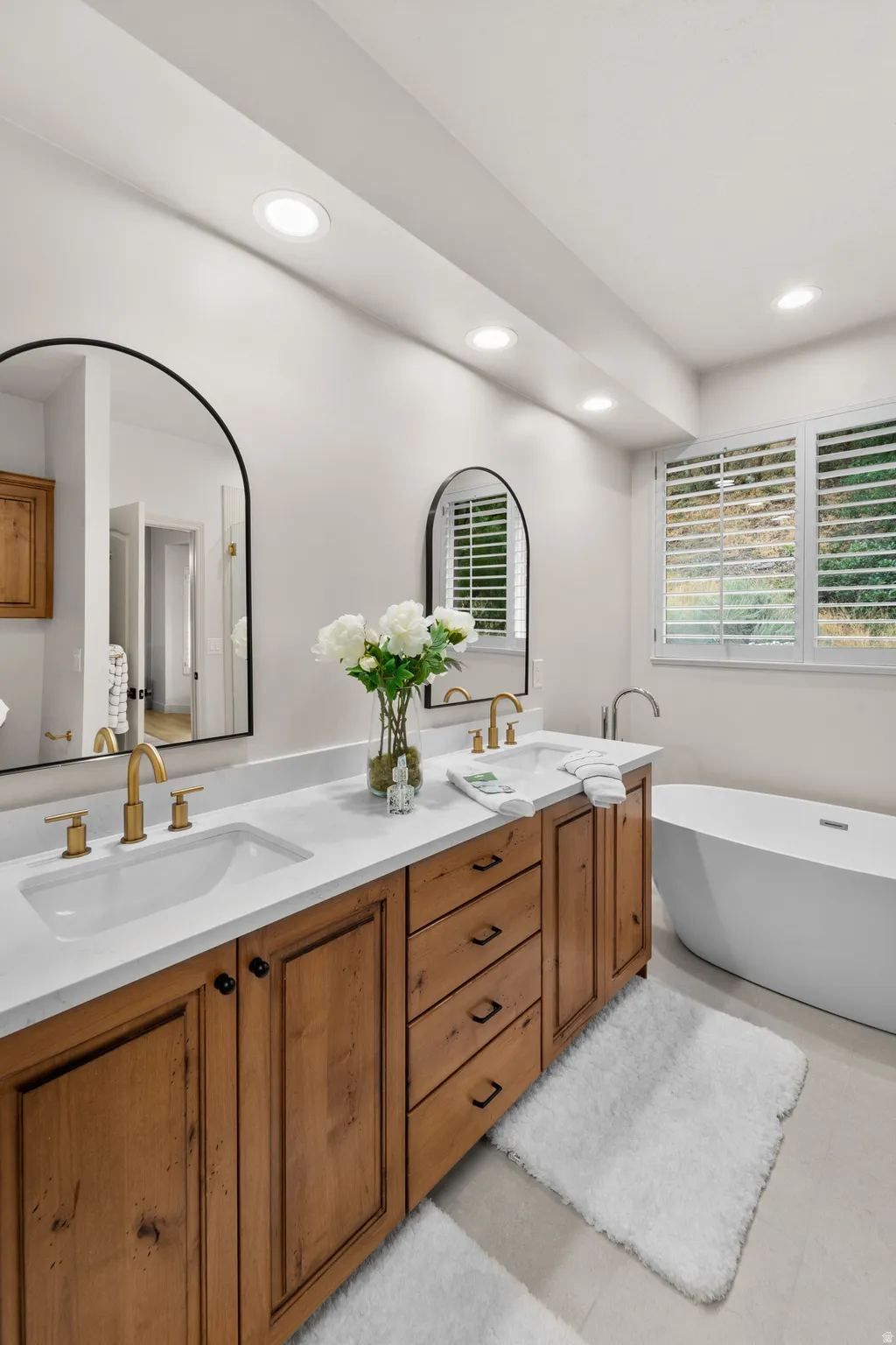 Dual vanity with white undermount sinks, wood cabinetry, and gold-toned fixtures