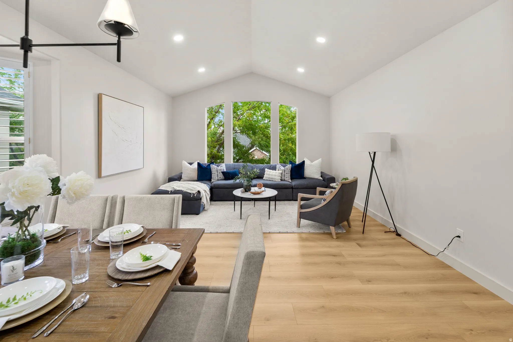 Vaulted ceiling with recessed lighting, light wood-finish flooring, and white walls