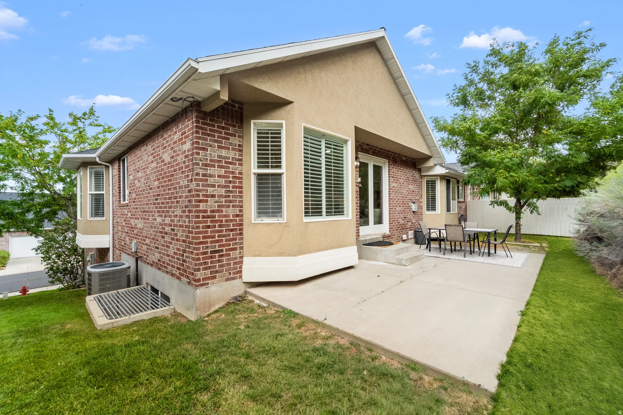 Exterior featuring brick and stucco siding, bay windows, and a concrete patio