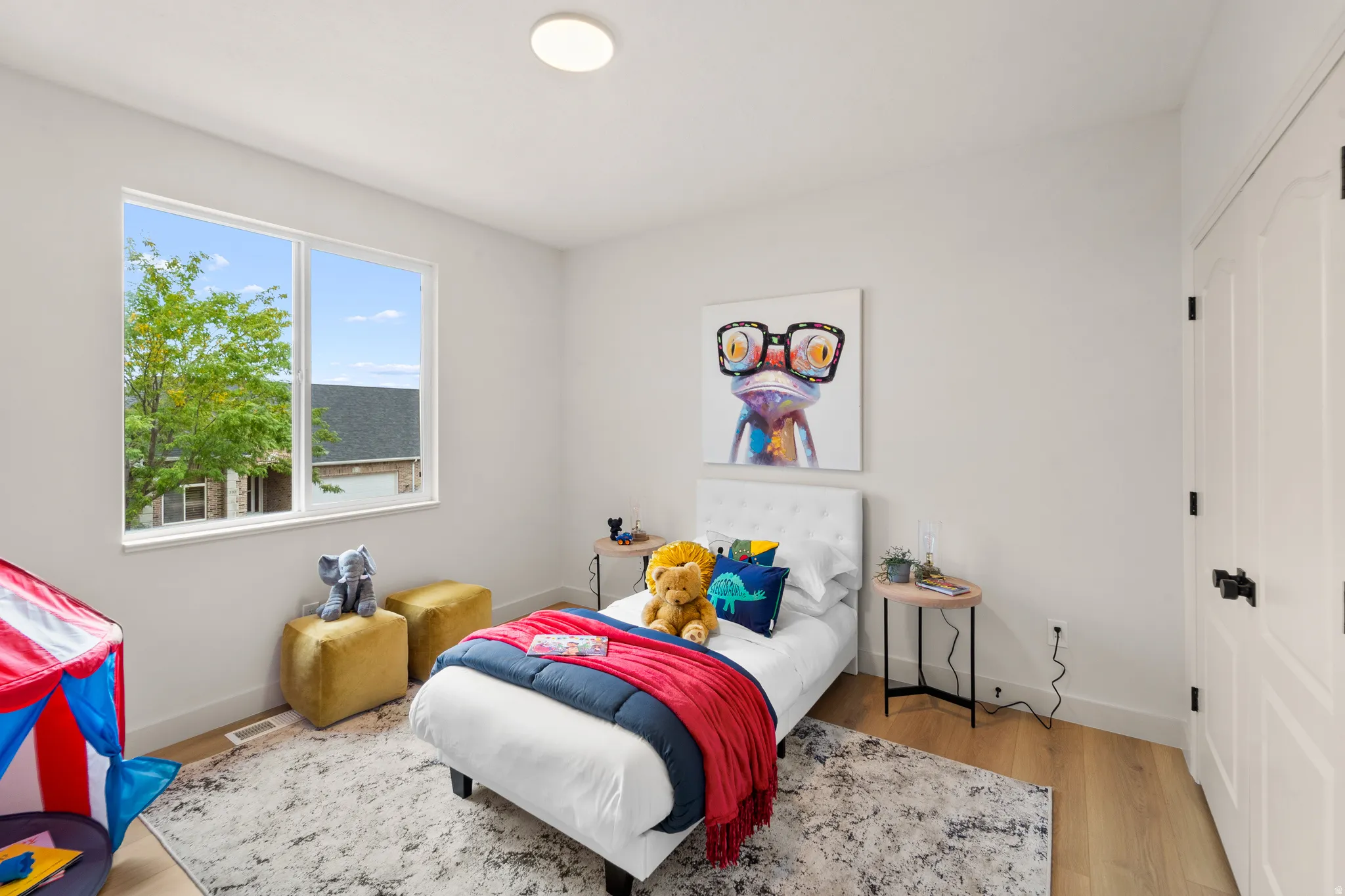 Large window with white trim, light wood-finish flooring, white walls, and a flat-panel ceiling light fixture