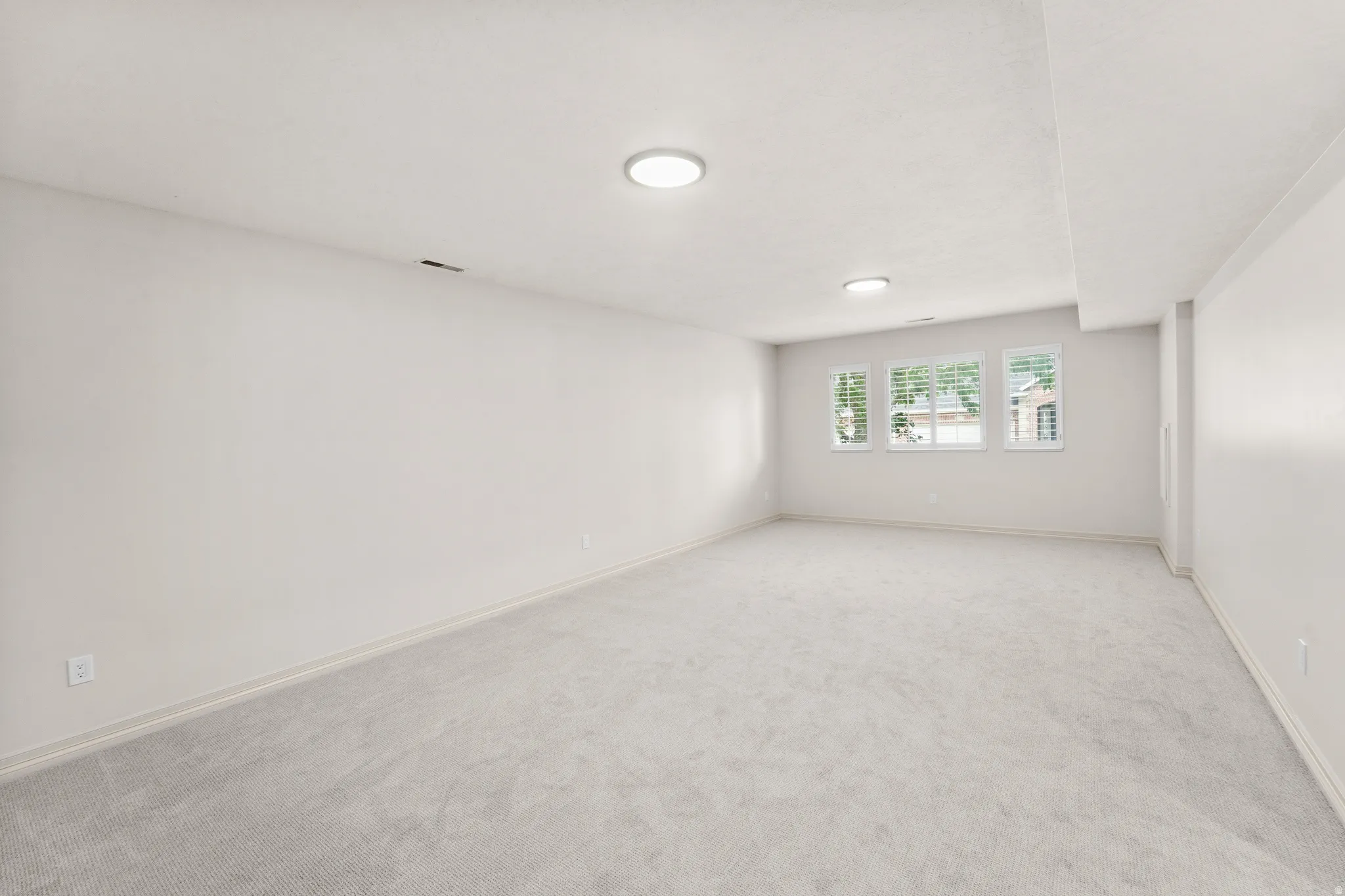 Expansive room with neutral carpeting and light-colored walls