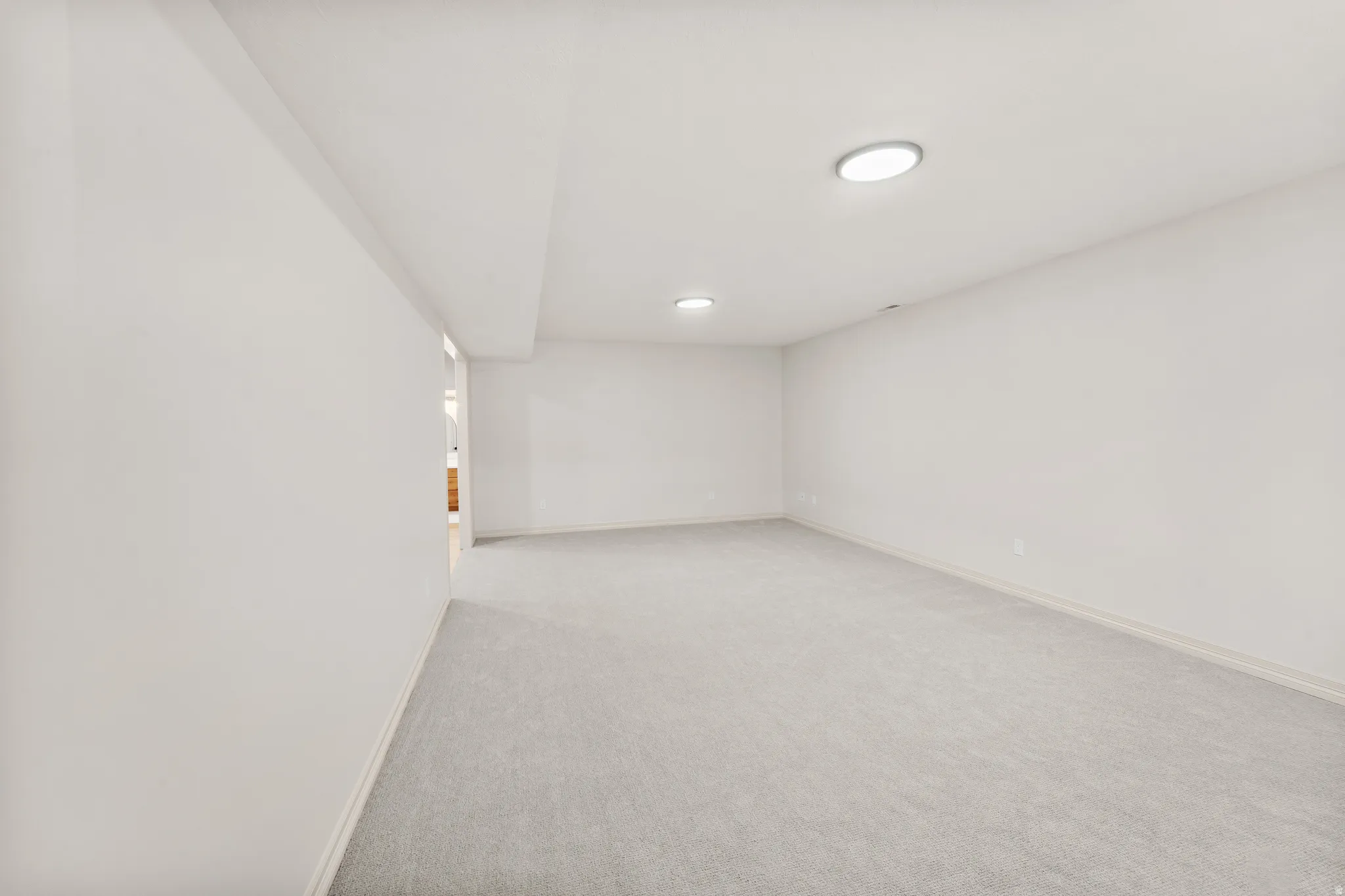 Recessed lighting illuminates the carpeted flooring and light-toned walls