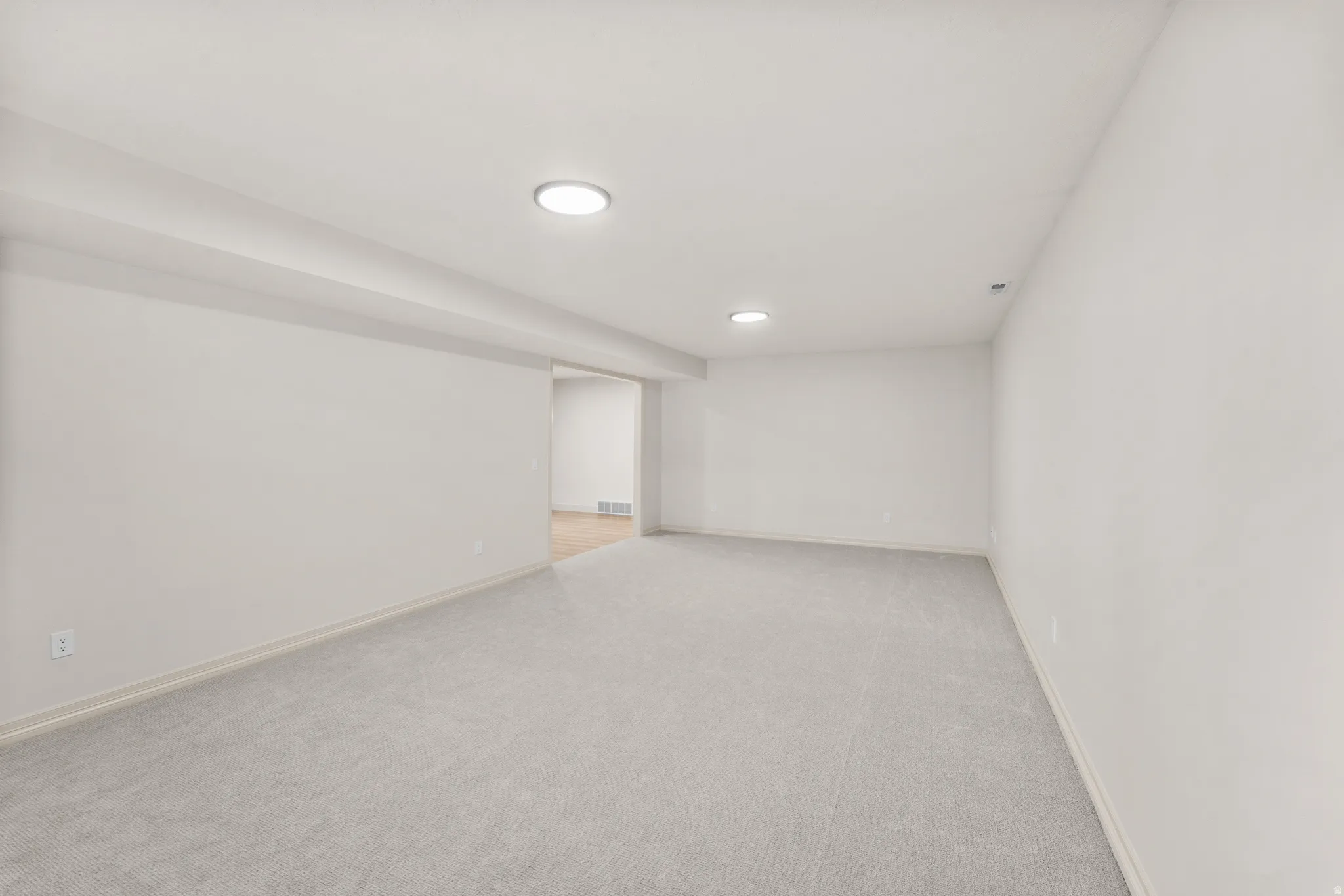 Expansive room with neutral carpeting and recessed lighting
