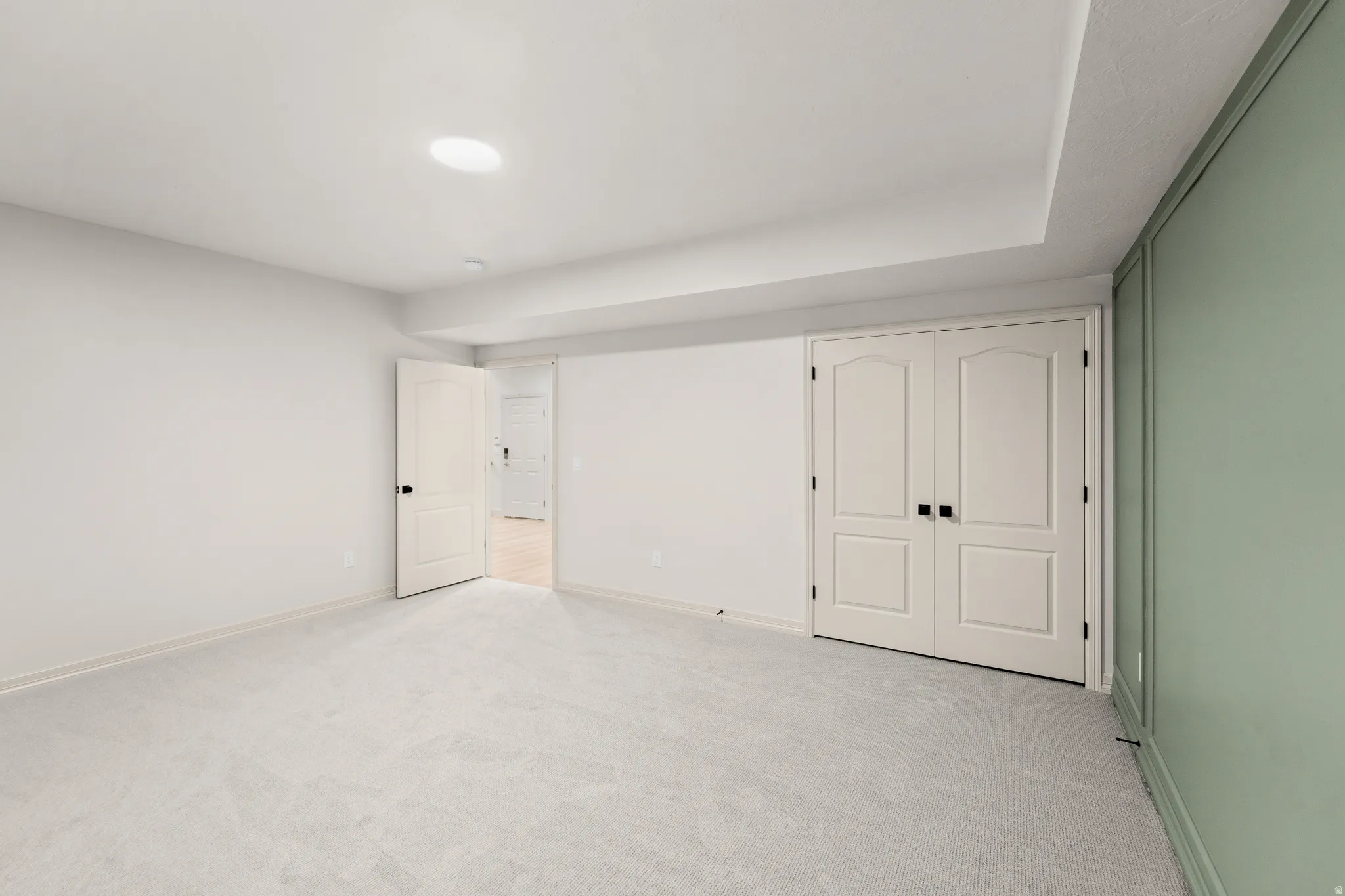Recessed lighting, plush carpeting, paneled interior doors, and a decorative accent wall