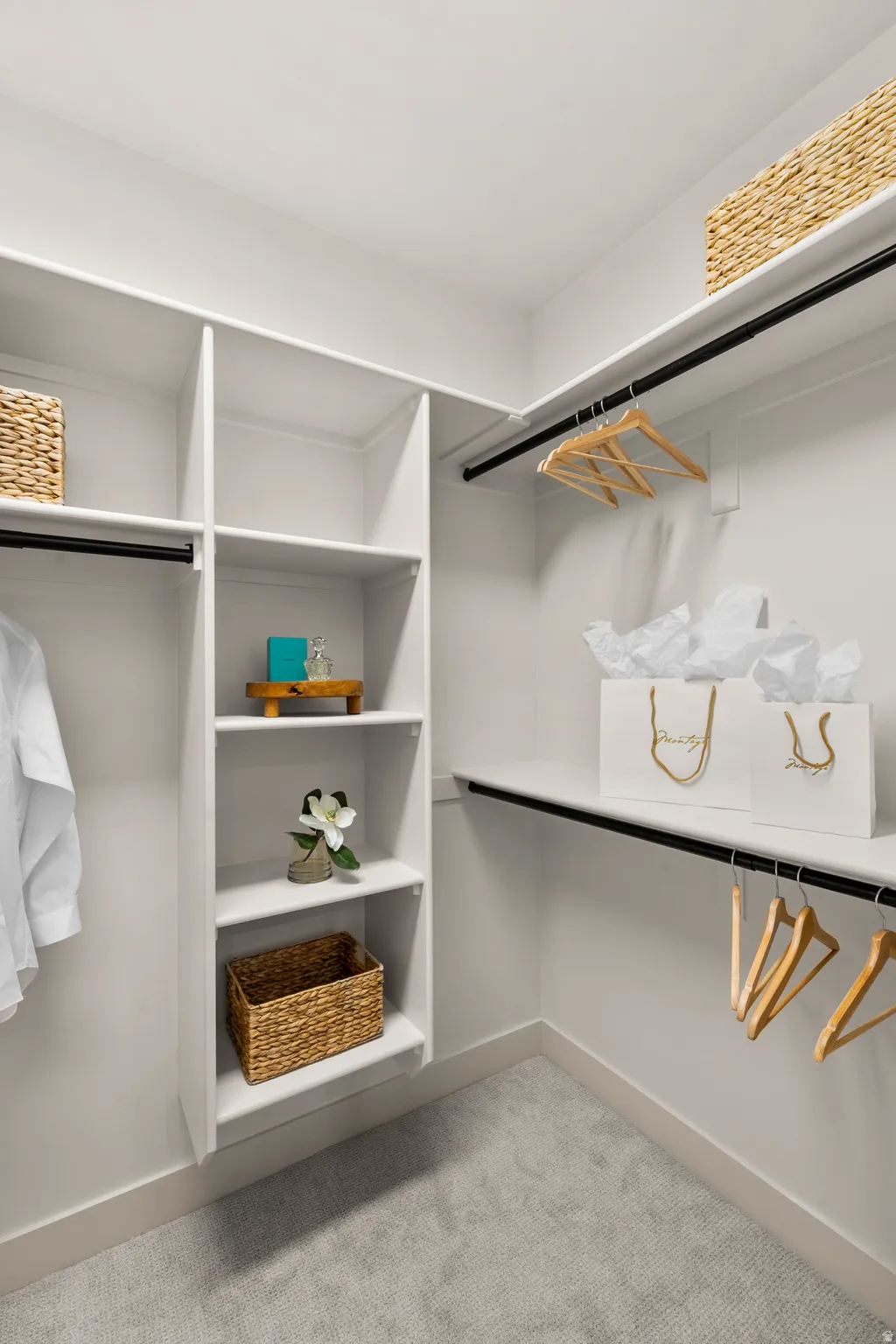 Built-in closet system featuring multiple shelves and hanging rods, white-painted cabinetry, and carpeting