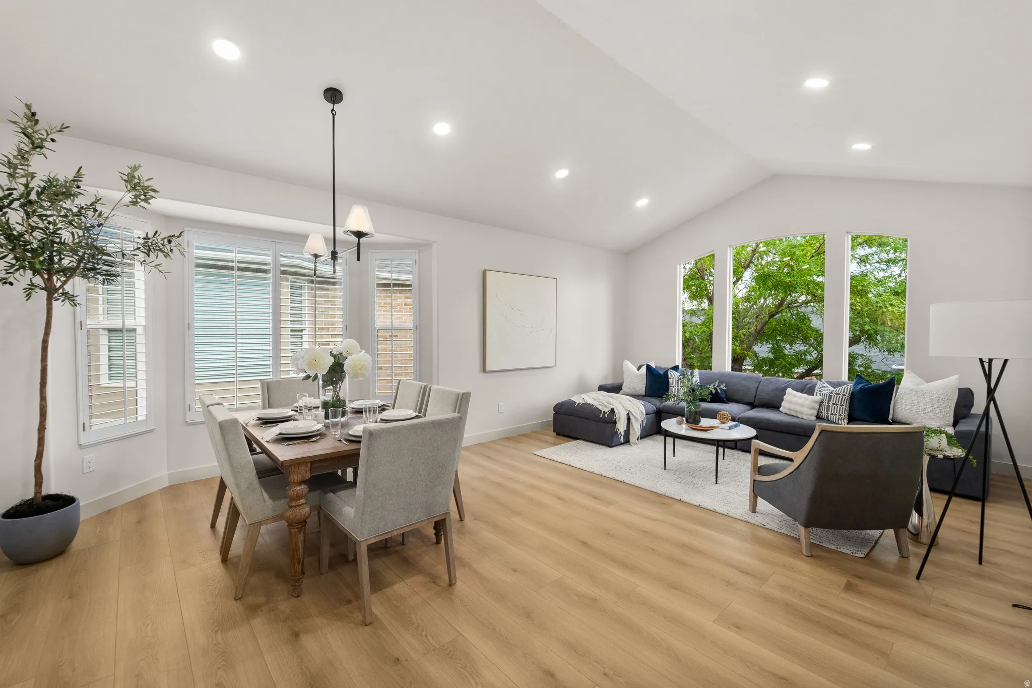 Vaulted ceilings with recessed lighting, wood-finish flooring, bay window with plantation shutters, large picture windows, and a hanging chandelier