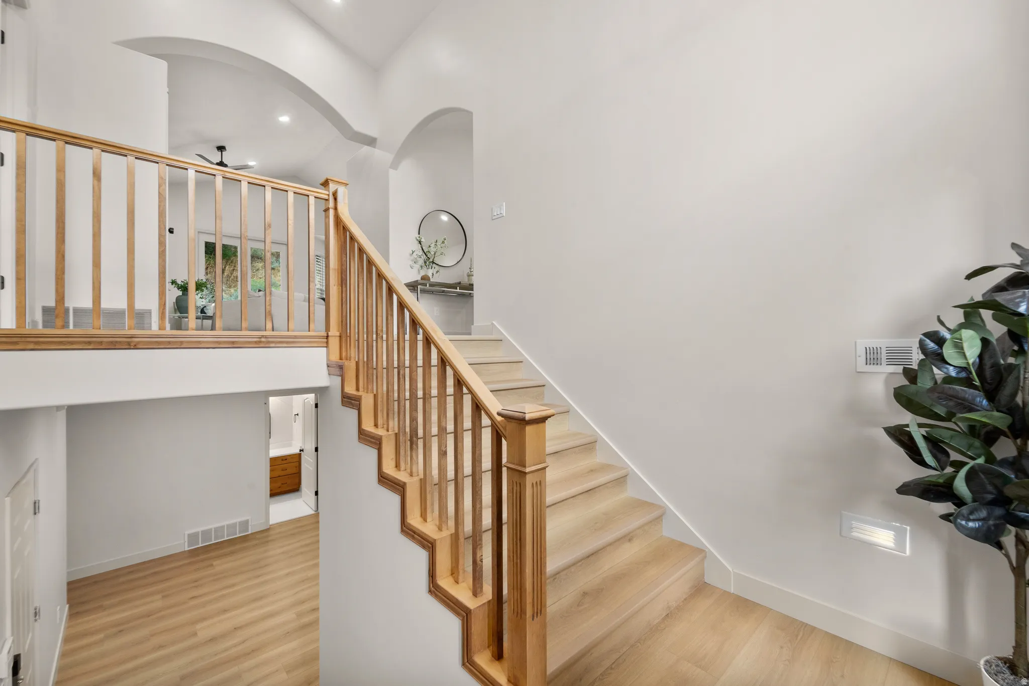 Split-level staircase featuring light wood-finish treads and railings