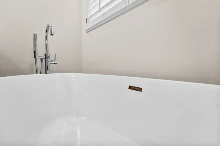 Freestanding soaking tub with a polished chrome floor-mounted tub filler and handheld shower attachment