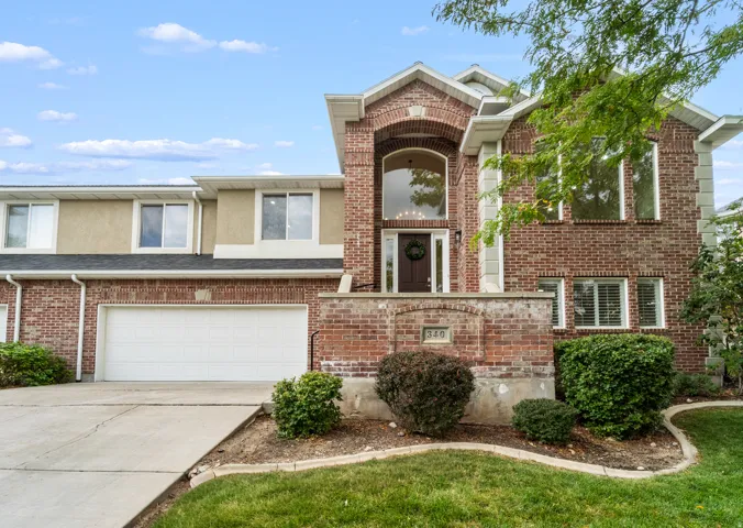 Brick exterior with a prominent arched entry, two-car garage, and established landscaping