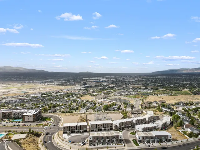 Expansive suburban landscape featuring modern townhomes, developed residential areas, and distant mountainous terrain under a clear sky
