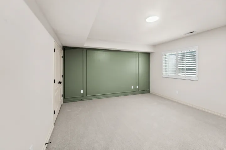 Wall paneling accent, recessed lighting, wall-to-wall carpeting, and a window with plantation shutters