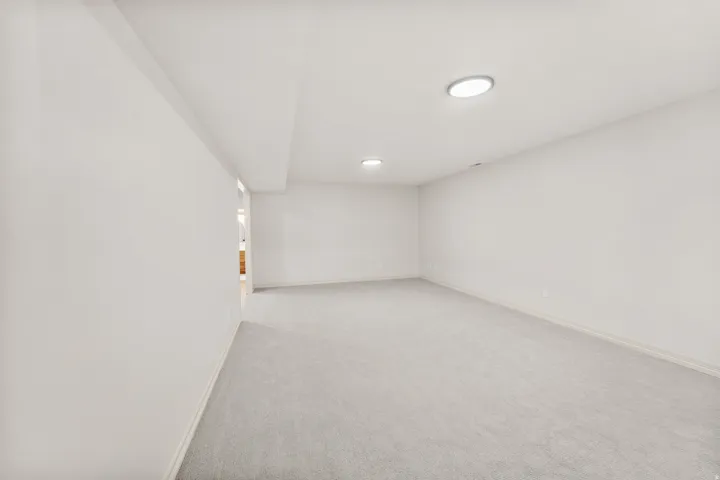 Recessed lighting illuminates the carpeted flooring and light-toned walls