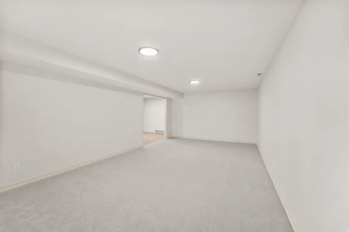 Expansive room with neutral carpeting and recessed lighting
