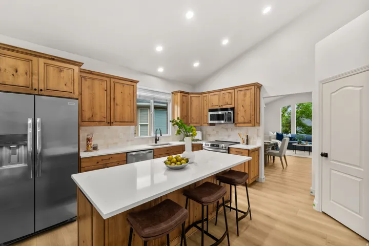Kitchen featuring wood-finish cabinetry, stainless steel appliances, a center island with counter seating, and light-tone wood-finish flooring