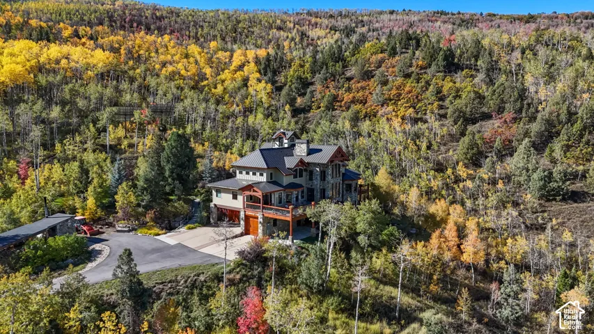 Multi-level residence with a stone and siding exterior, dark-toned roof, and expansive elevated decking