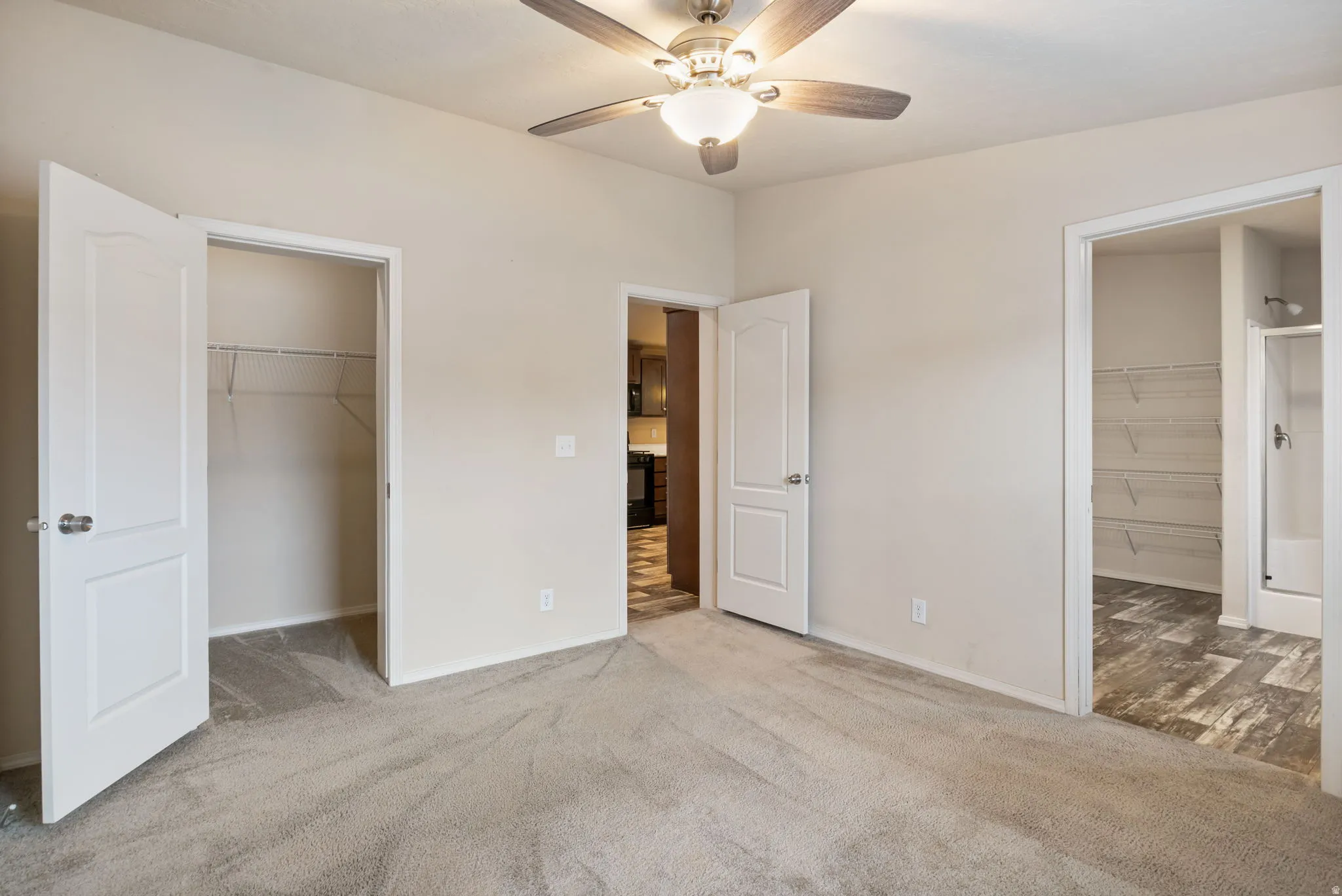 Neutral tone wall paint, carpeted flooring, ceiling fan with integrated lighting, white paneled doors, wire shelving in closet