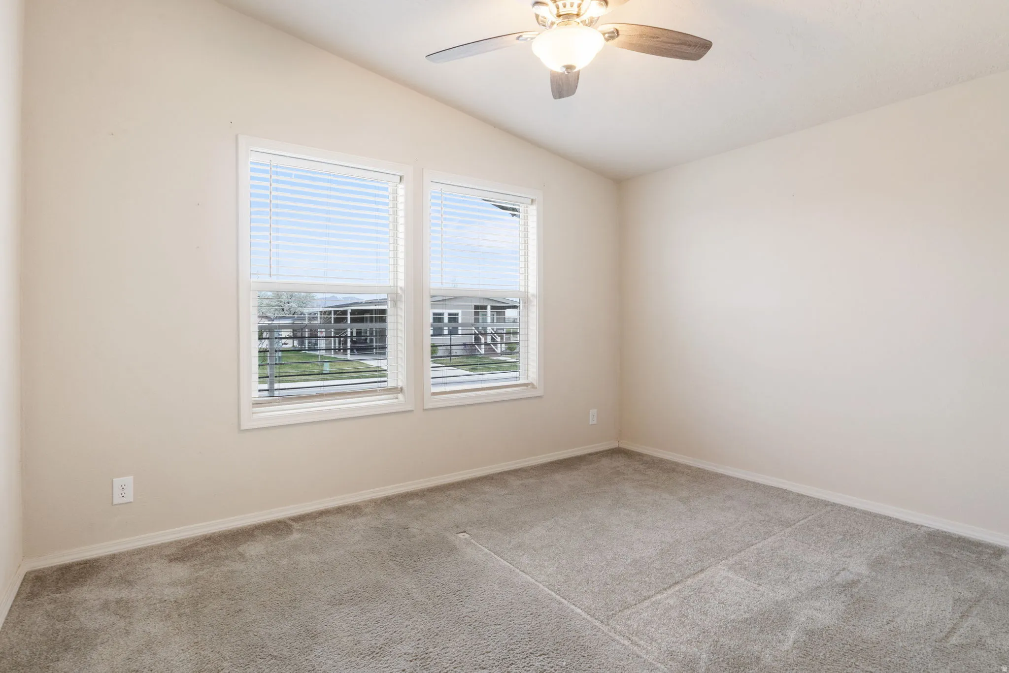 Vaulted ceiling with a ceiling fan, two windows, wall-to-wall carpeting