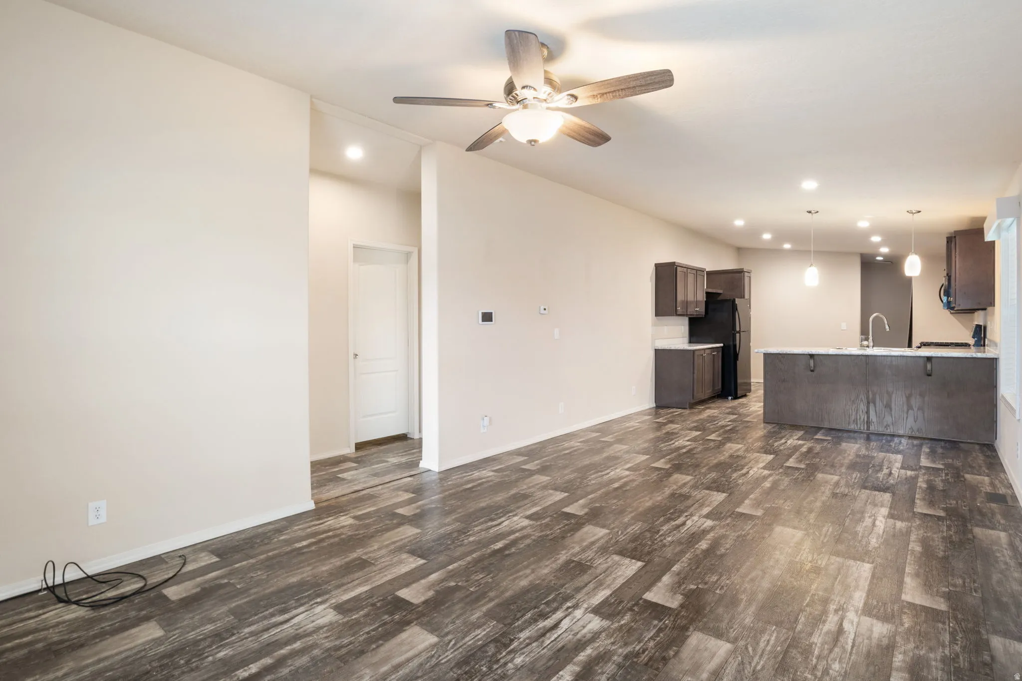 Wood-finish flooring throughout the main living space, complemented by recessed lighting and a ceiling fan