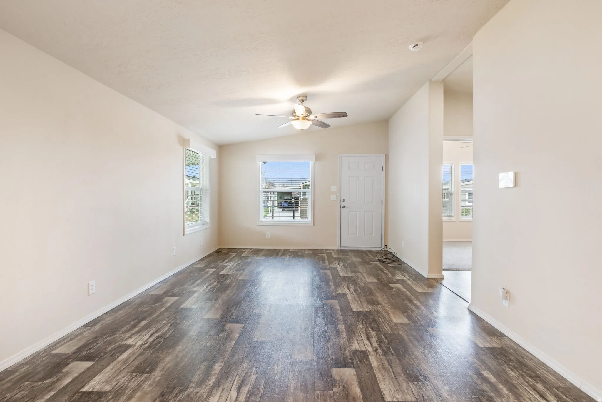 Vaulted ceiling, wood-finish flooring, ceiling fan, natural light, and a paneled entry door