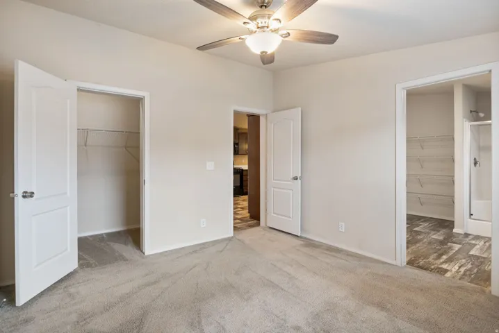 Neutral tone wall paint, carpeted flooring, ceiling fan with integrated lighting, white paneled doors, wire shelving in closet