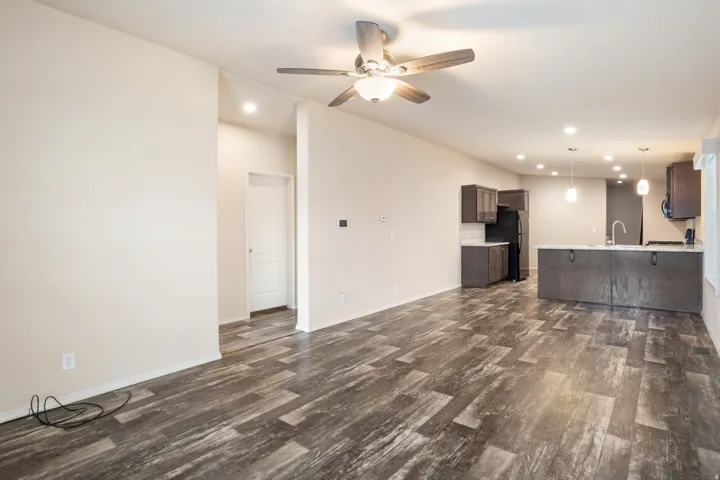 Wood-finish flooring throughout the main living space, complemented by recessed lighting and a ceiling fan