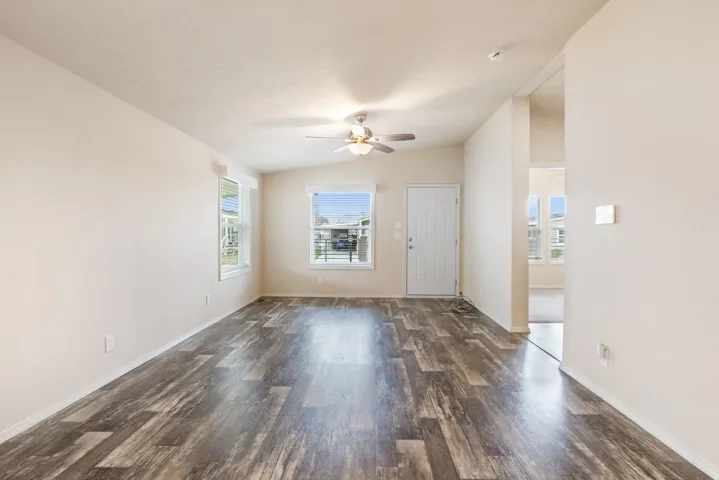 Vaulted ceiling, wood-finish flooring, ceiling fan, natural light, and a paneled entry door