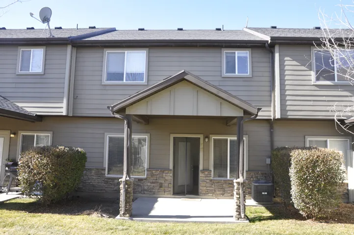 Rear exterior featuring a covered patio, stone veneer accents, and horizontal siding