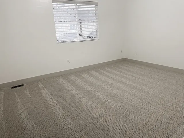 Window with blinds, wall-to-wall carpeting, and neutral wall tones