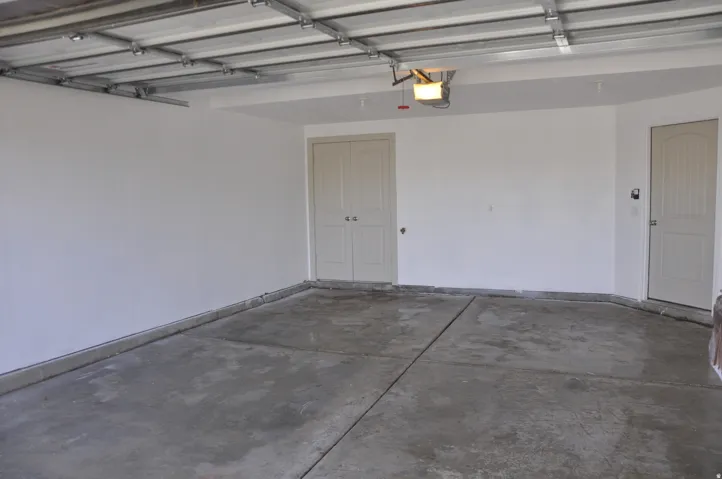 Spacious garage with concrete flooring, automatic garage door opener, and two access doors