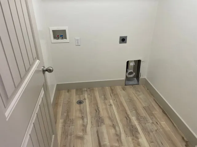 Wood-finish flooring with a floor drain, a utility sink connection, and a dryer vent