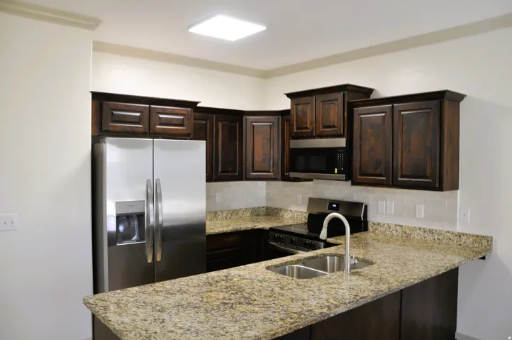 Kitchen featuring dark wood cabinetry, granite countertops, a stainless steel side-by-side refrigerator, and a stainless steel sink with a gooseneck faucet