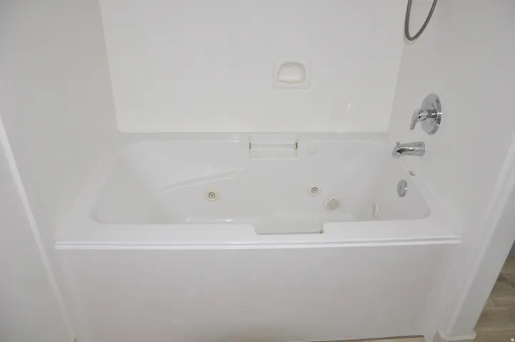 White jetted bathtub with a chrome faucet and shower head