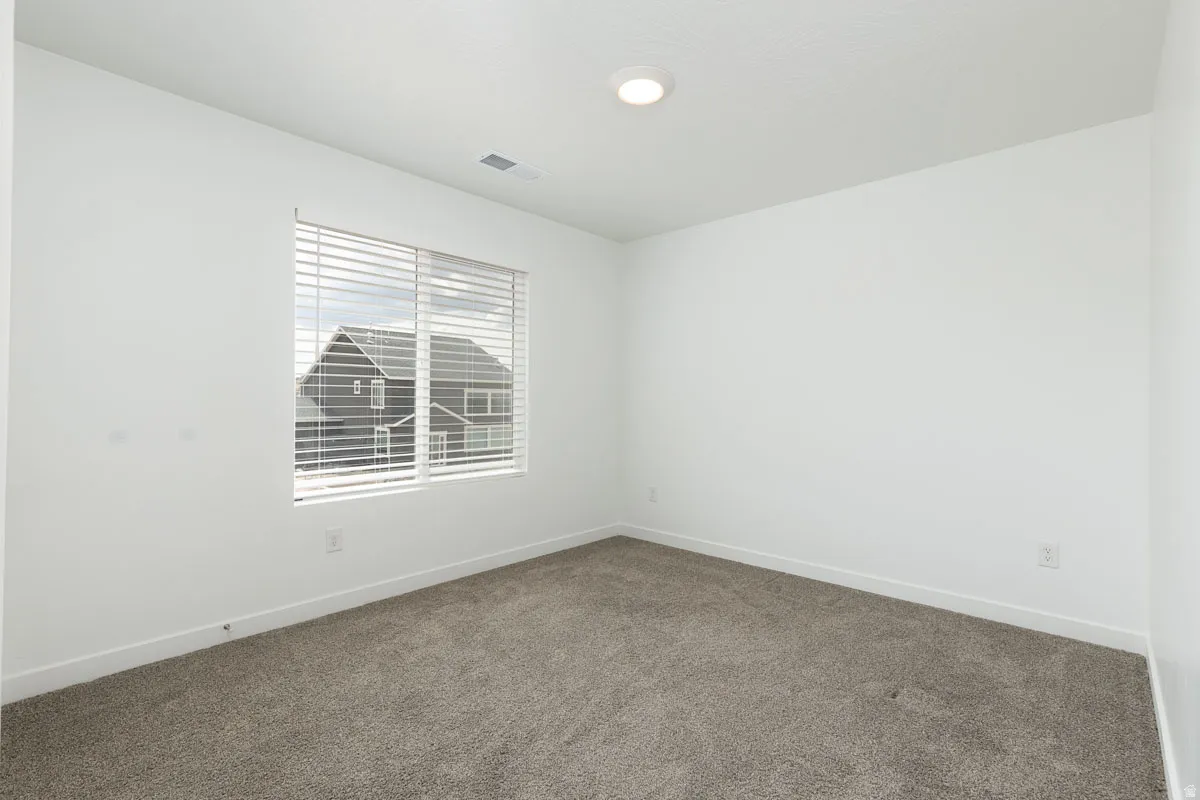 Neutral wall paint, recessed ceiling light, window with horizontal blinds, and carpeted flooring