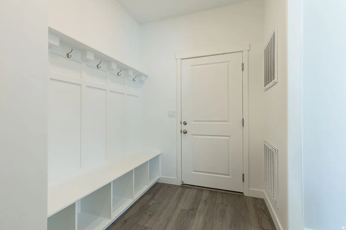 Built-in bench with cubby storage, wall-mounted coat hooks, and wood-finish flooring